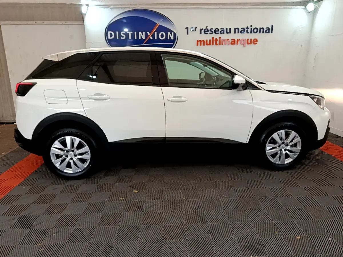 Profil côté gauche d’un SUV Peugeot 3008 blanc avec toit noir, dans un showroom au sol damier gris et rouge.
