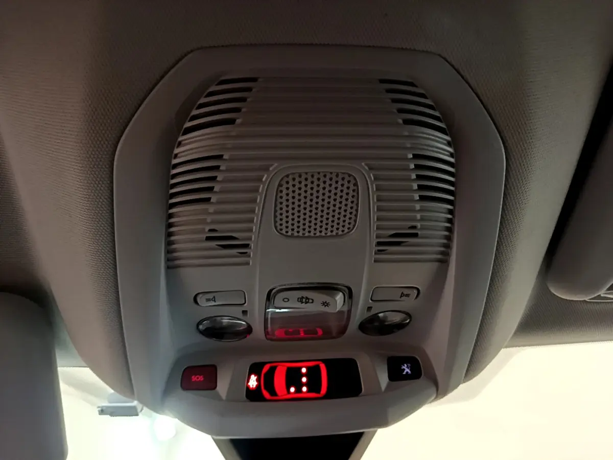 Vue en gros plan du plafonnier intérieur gris avec boutons de contrôle et témoin rouge allumé dans un Peugeot 3008 blanc