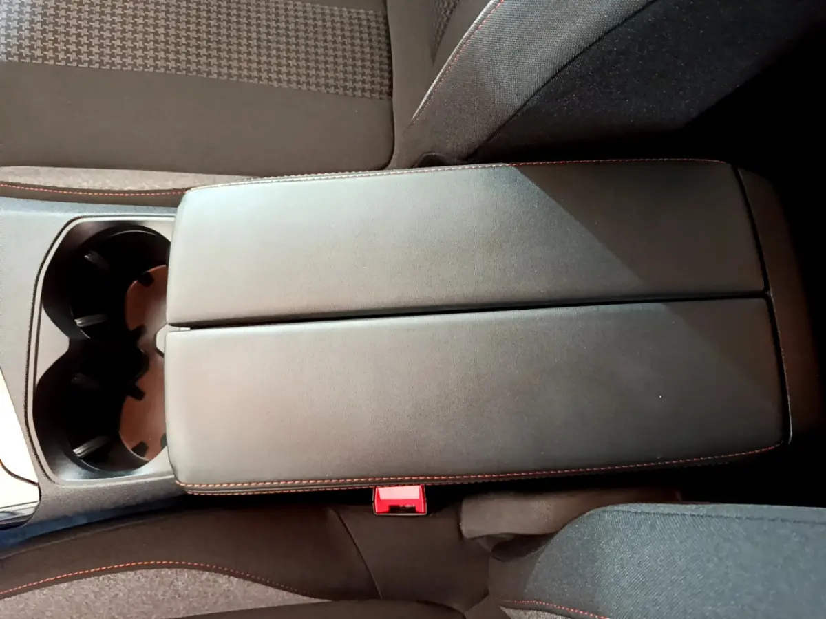 Accoudoir central noir avec surpiqûres rouges et porte-gobelets dans l'habitacle du Peugeot 3008 blanc 2020.