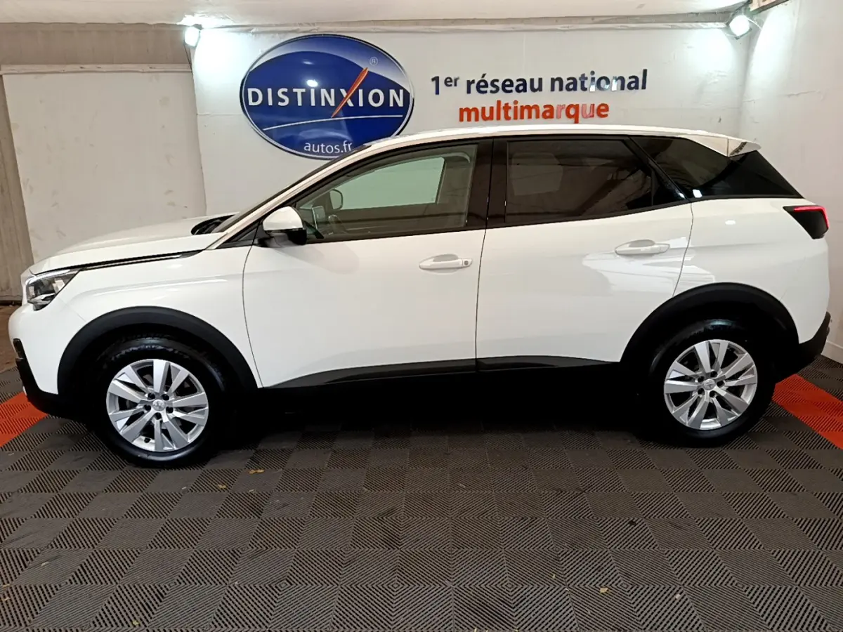 Profil côté gauche d'un Peugeot 3008 blanc 2020 avec jantes alliage et vitres teintées, en intérieur showroom.