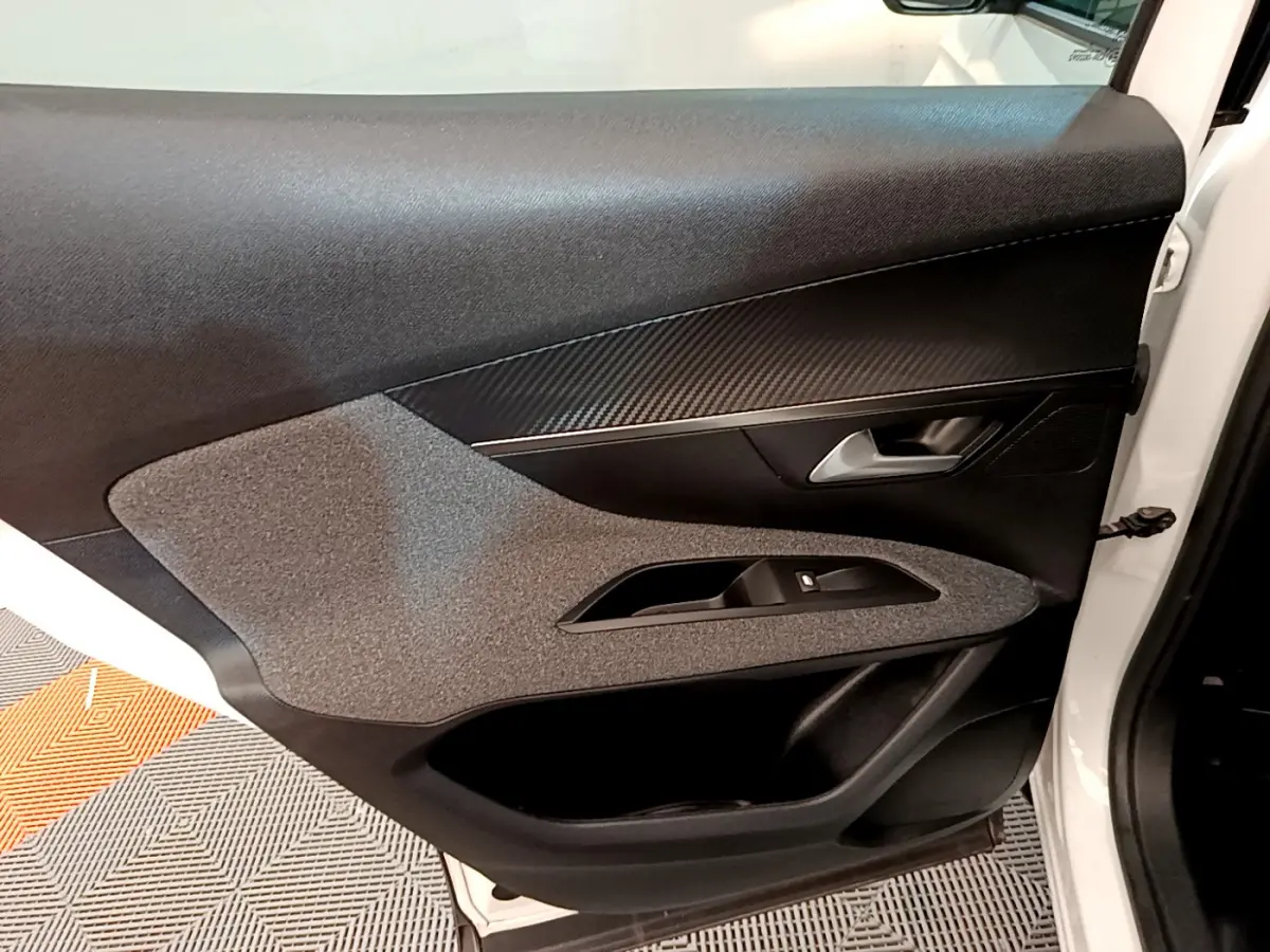 Gros plan sur la porte avant gauche blanche d'un Peugeot 3008 2020, avec garniture noire et inserts effet carbone.