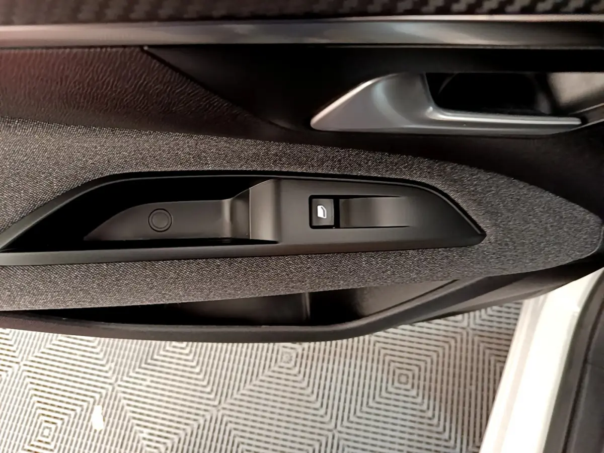 Poignée intérieure et commande de lève-vitre côté gauche du Peugeot 3008 blanc, finition tissu gris.