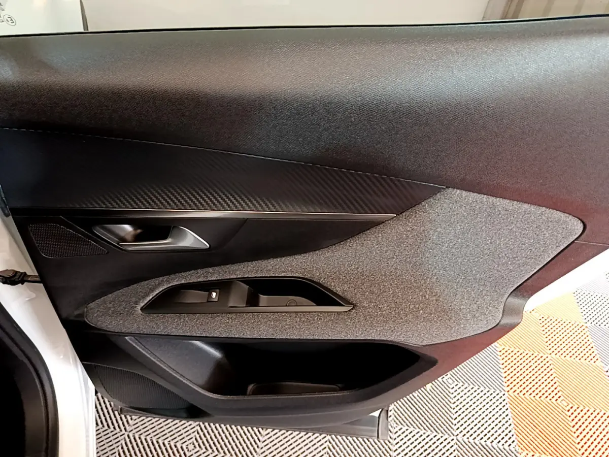 Porte intérieure côté gauche du Peugeot 3008 blanc, avec habillage noir et gris texturé et poignée argentée.