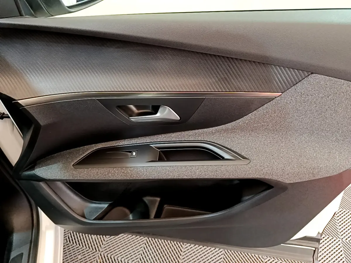 Vue rapprochée de la porte avant gauche du Peugeot 3008 blanc, mettant en valeur les textures et la poignée intérieure.