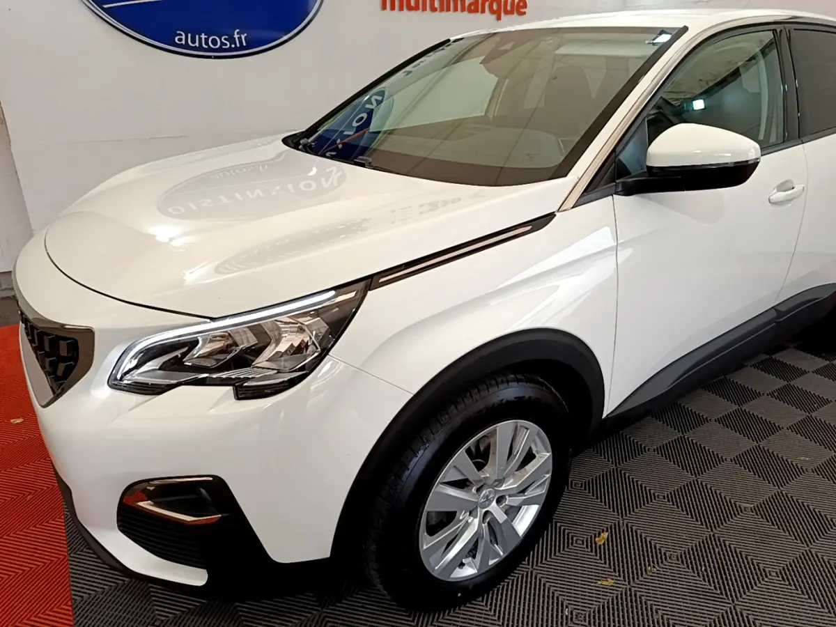 Vue 3/4 avant droit d'un Peugeot 3008 blanc avec phares LED et jantes alliage dans un showroom.