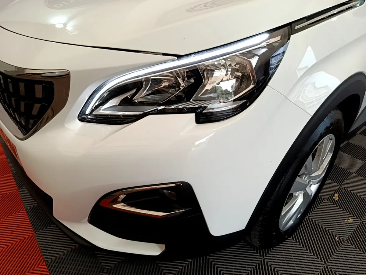 Gros plan sur l'avant droit blanc du Peugeot 3008 2020, mettant en valeur le phare et la calandre distinctive.