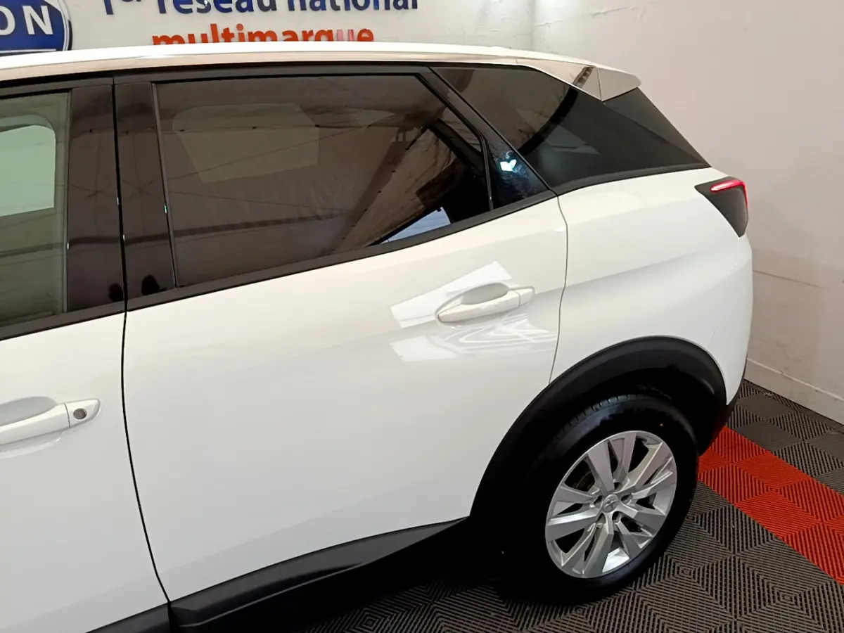 Vue latérale droite du Peugeot 3008 blanc avec vitres teintées et jantes alliage, arrière du SUV en intérieur showroom.