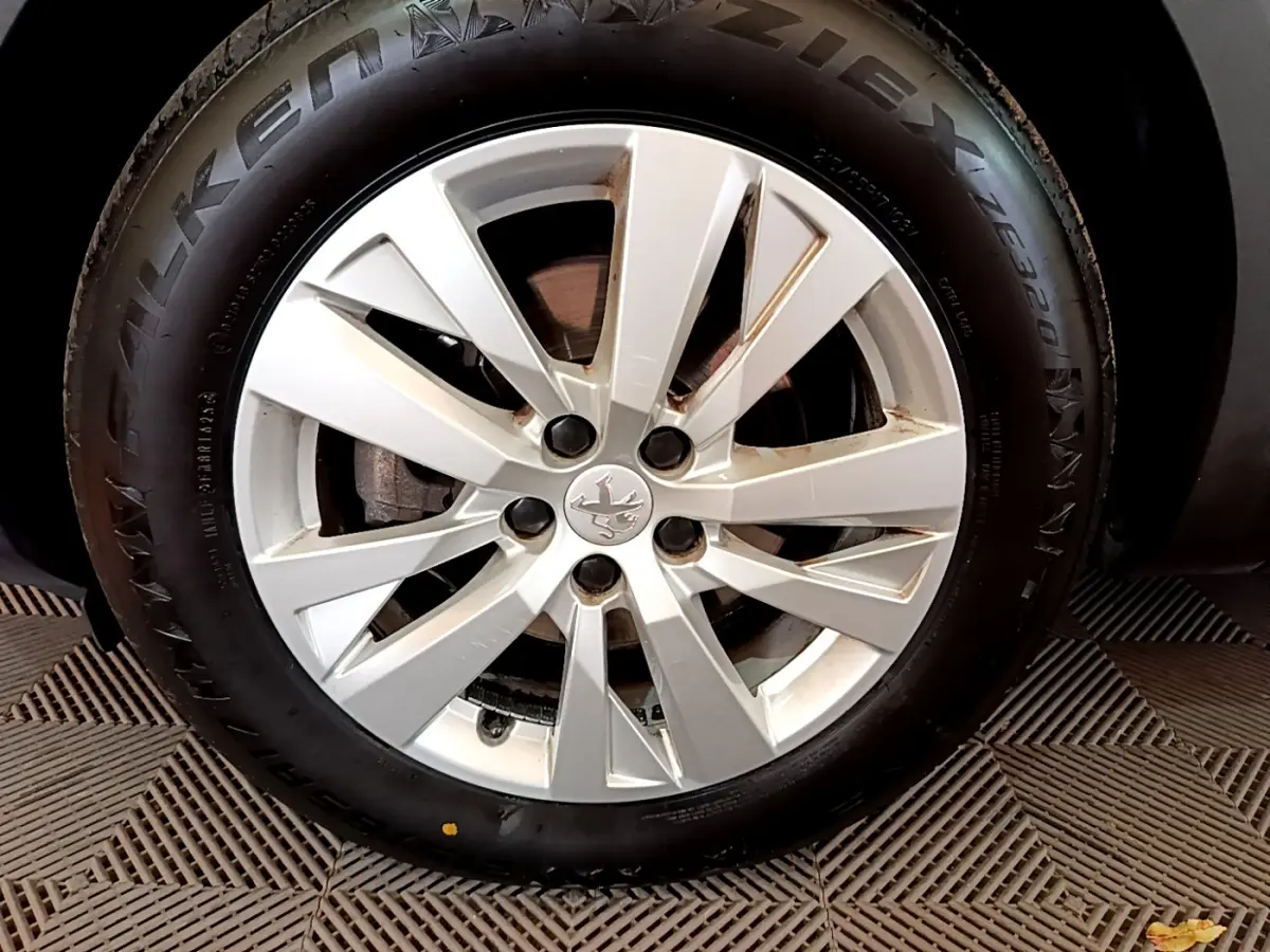 Gros plan sur la roue avant gauche d'un Peugeot 3008 blanc, avec jante alliage et pneu Falken visible.