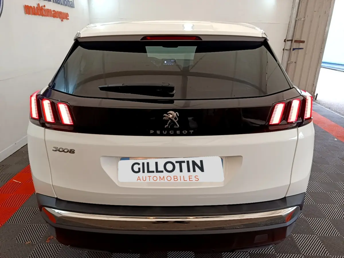 Vue arrière d'un Peugeot 3008 blanc avec feux arrière LED caractéristiques et bande noire brillante centrale.