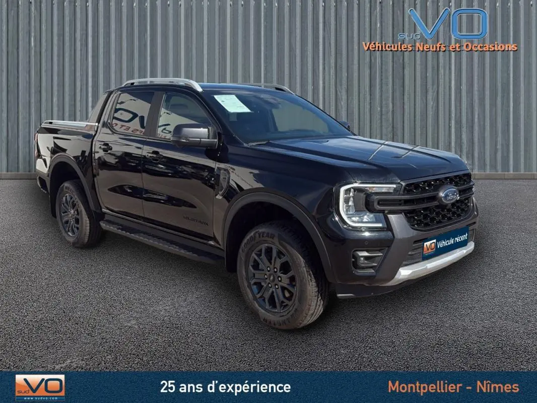 Ford Ranger Wildtrak noir en 3/4 avant droit, avec barres de toit, marchepieds et jantes alliage 18 pouces.