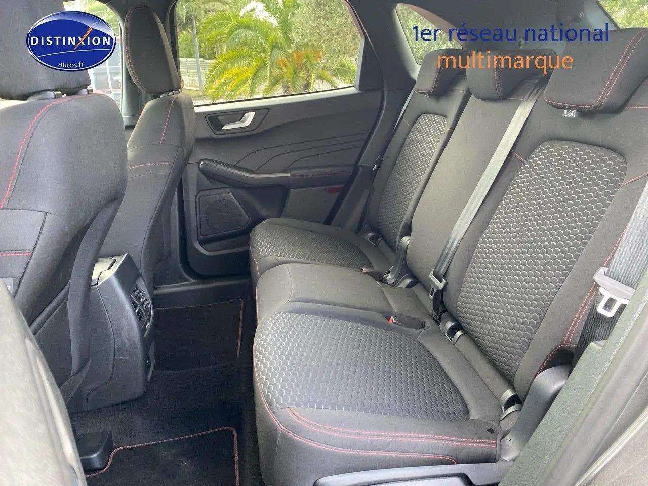 Vue intérieure des sièges arrière du Ford Kuga 2025 avec tissu noir et surpiqûres rouges, côté droit ouvert.