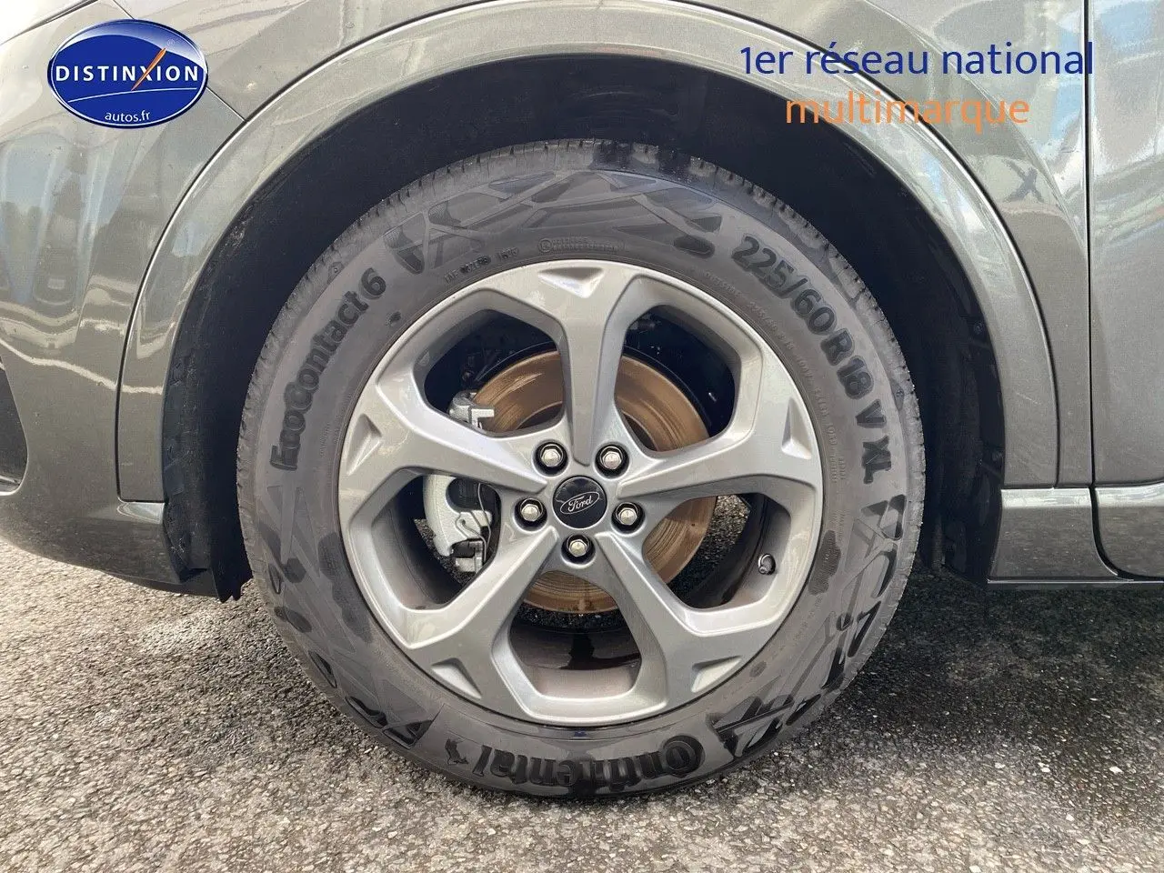 Gros plan sur la roue avant droite en jante alu gris d’un Ford Kuga gris Magnetic Fashion Métallisée.