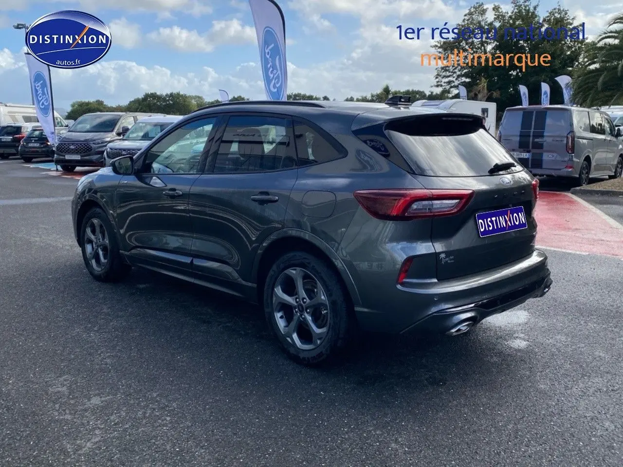 Ford Kuga gris Magnetic Fashion vue 3/4 arrière droit, avec jantes alu et feux arrière LED dans un parking extérieur.
