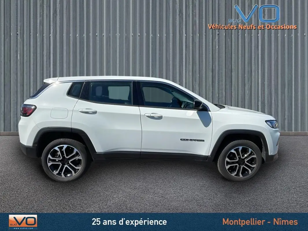 Profil côté gauche d'un Jeep Compass blanc 2024 avec jantes alliage 18 pouces sur fond industriel.