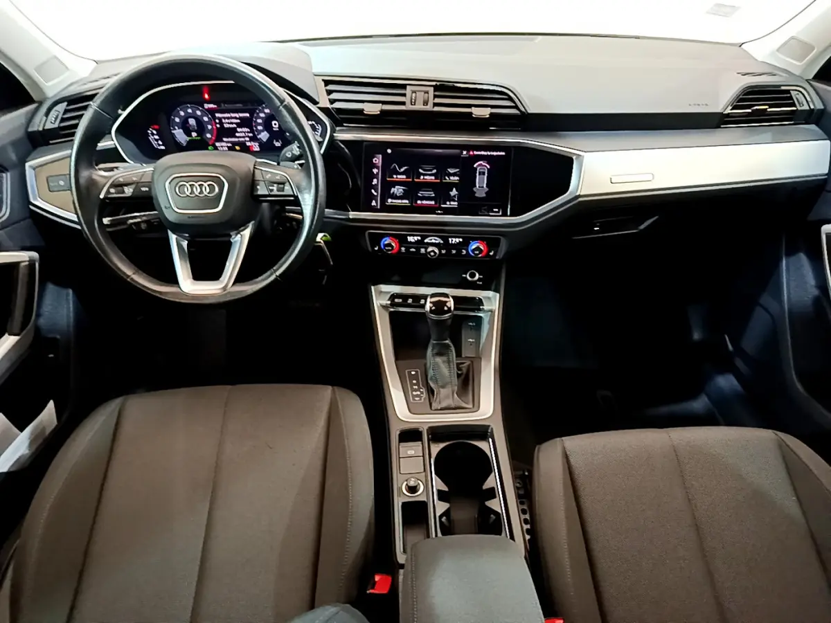 Intérieur Audi Q3 Sportback 2021 vu de face, tableau de bord noir avec écran tactile et volant cuir multifonctions.