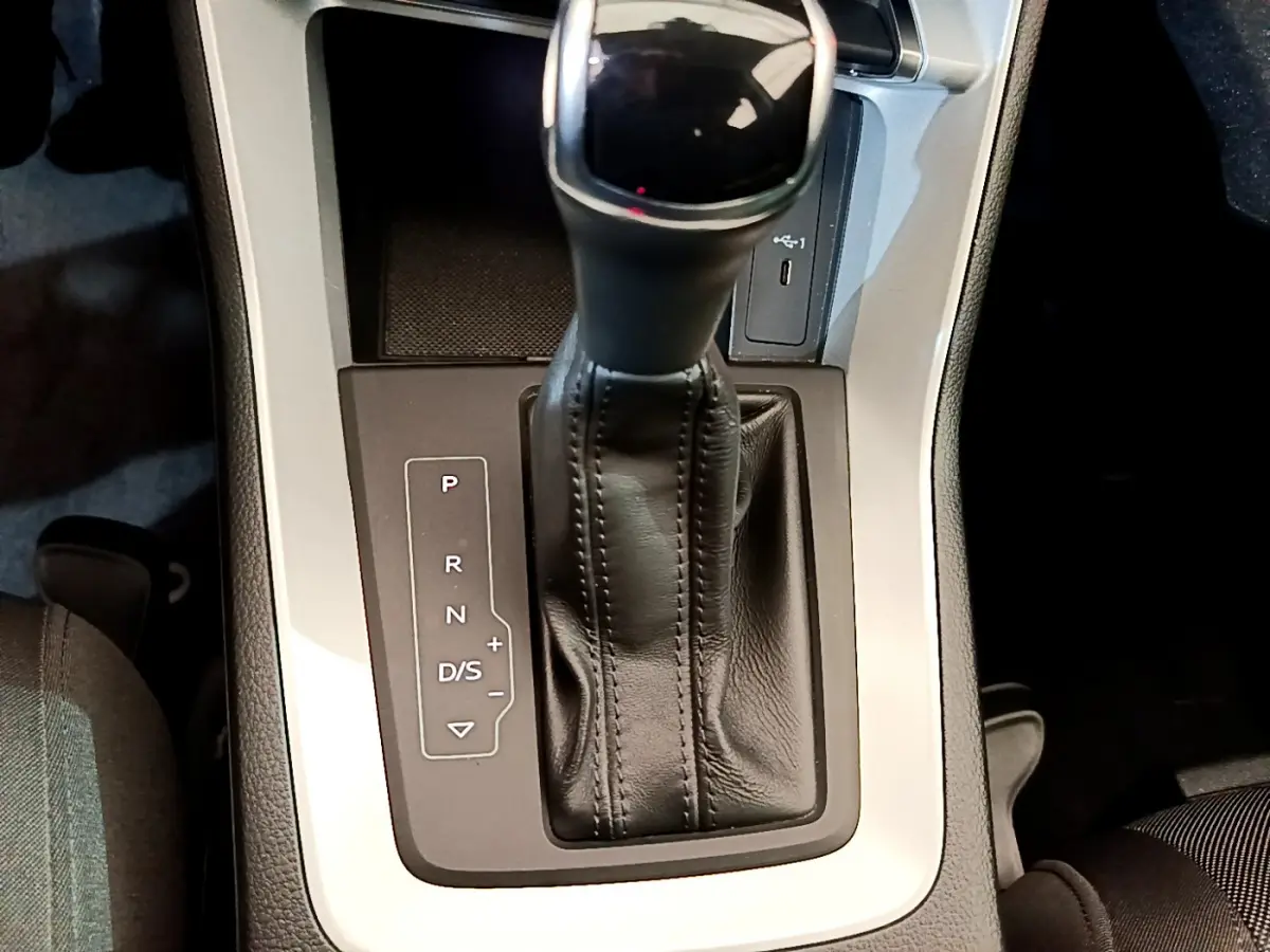Le levier de vitesses automatique noir de l'Audi Q3 Sportback 35 TFSI 150 MHEV vu de dessus, entouré de console grise.