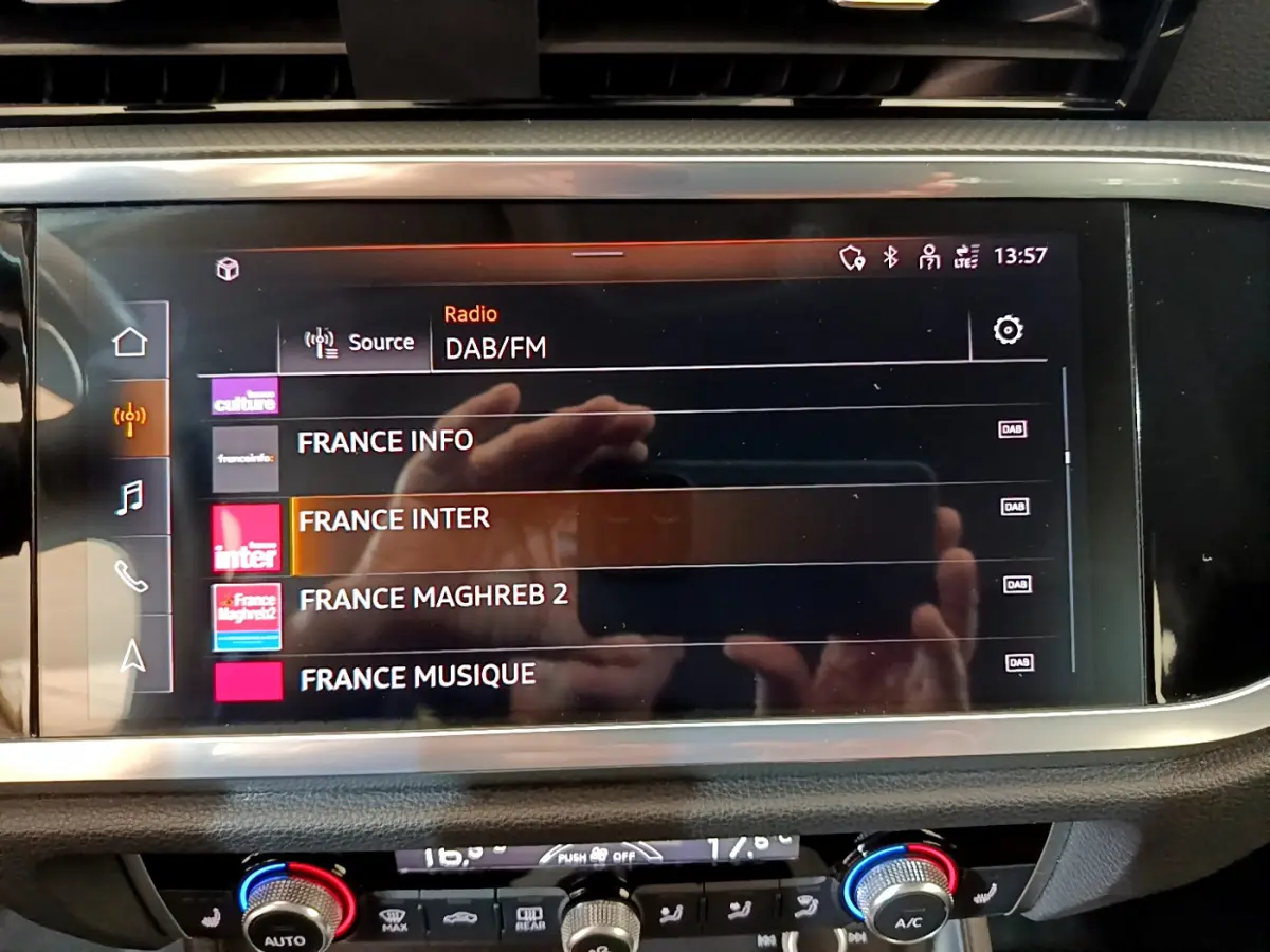 Écran tactile central de l'Audi Q3 Sportback 35 TFSI noir, affichant les stations radio DAB/FM en intérieur.