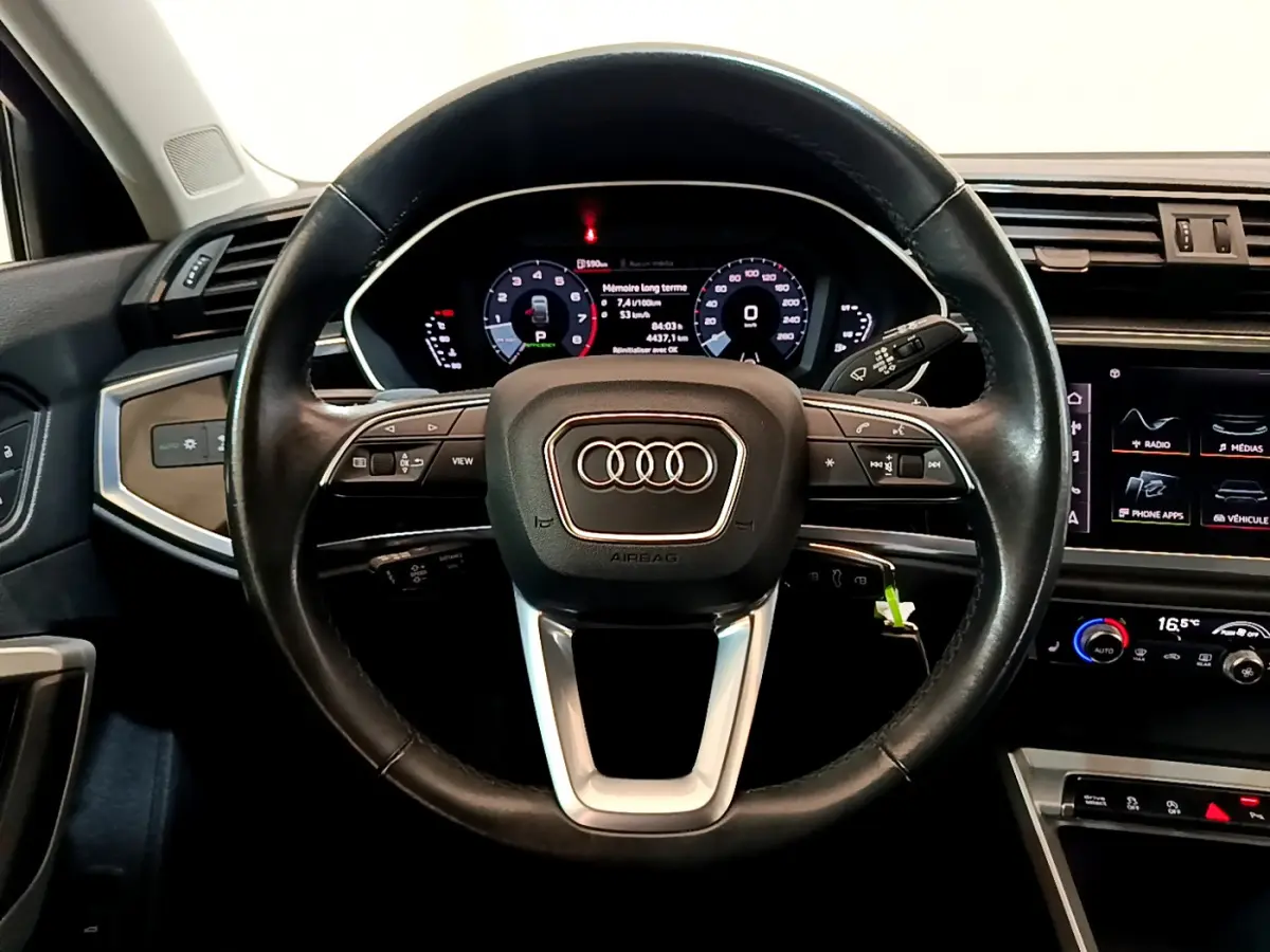 Volant cuir noir de l'Audi Q3 Sportback 35 TFSI 150 MHEV 2021 vu de face avec tableau de bord numérique et commandes intégrées.