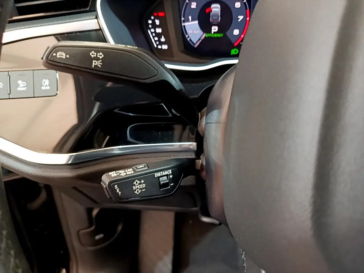 Gros plan sur les commandes au volant à gauche de l'Audi Q3 Sportback 35 TFSI noir, avec tableau de bord numérique visible.