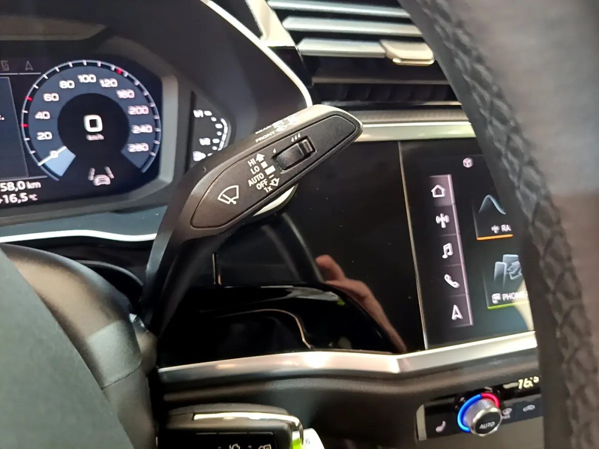 Gros plan sur la commande d'essuie-glace et le tableau de bord numérique d'un Audi Q3 Sportback noir, intérieur moderne.