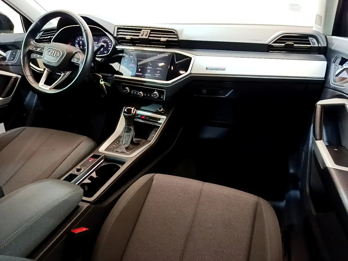 Intérieur Audi Q3 Sportback 2021 vu côté conducteur, tableau de bord noir avec écran tactile et volant cuir multifonctions.