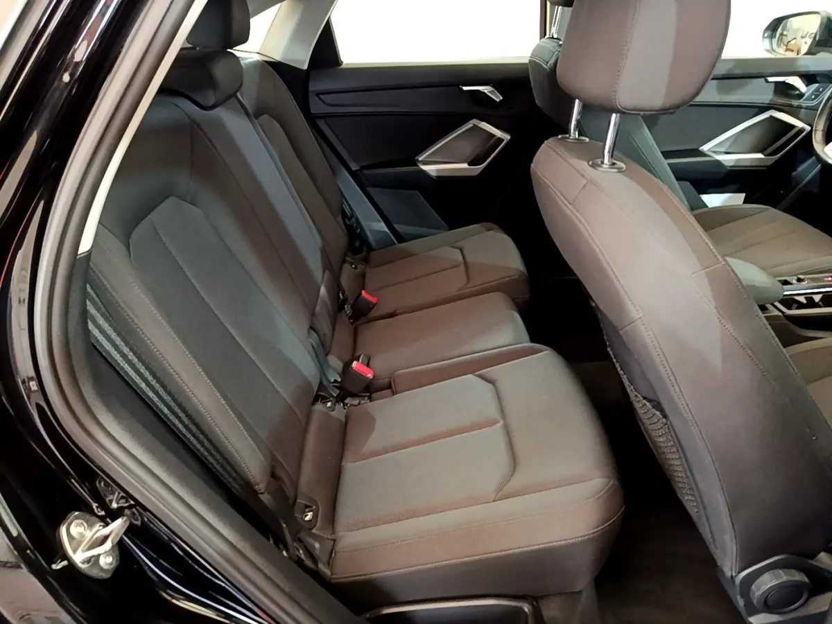 Vue intérieure côté gauche sur la banquette arrière et les sièges avant noirs de l'Audi Q3 Sportback 2021.