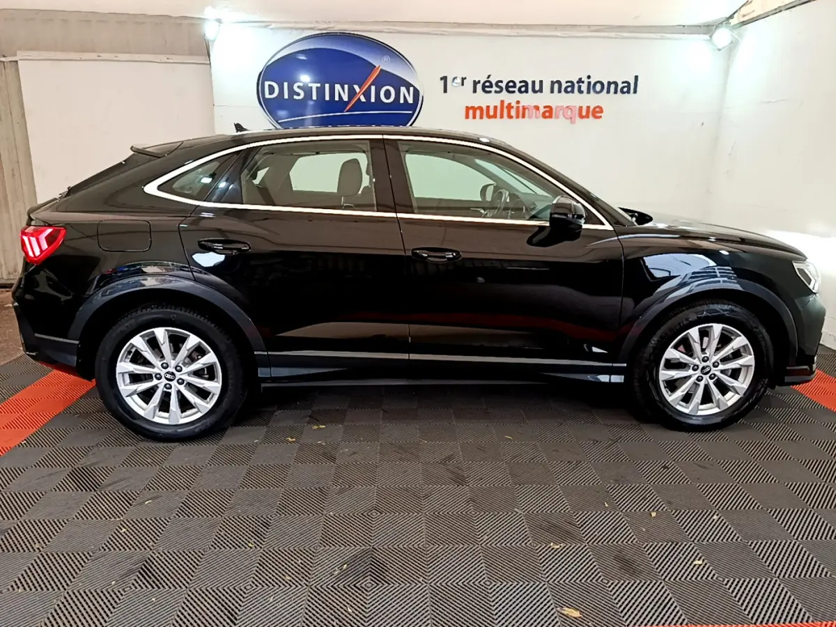 Audi Q3 Sportback noir vue de profil côté gauche, avec jantes argentées et feux arrière LED allumés.