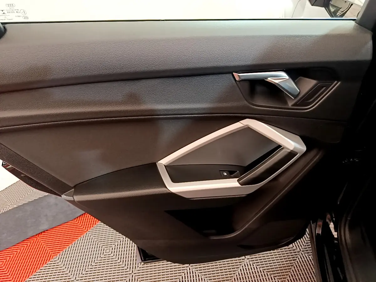 Gros plan sur la porte intérieure côté droit noire de l'Audi Q3 Sportback 2021 avec poignée argentée et commande de vitre.