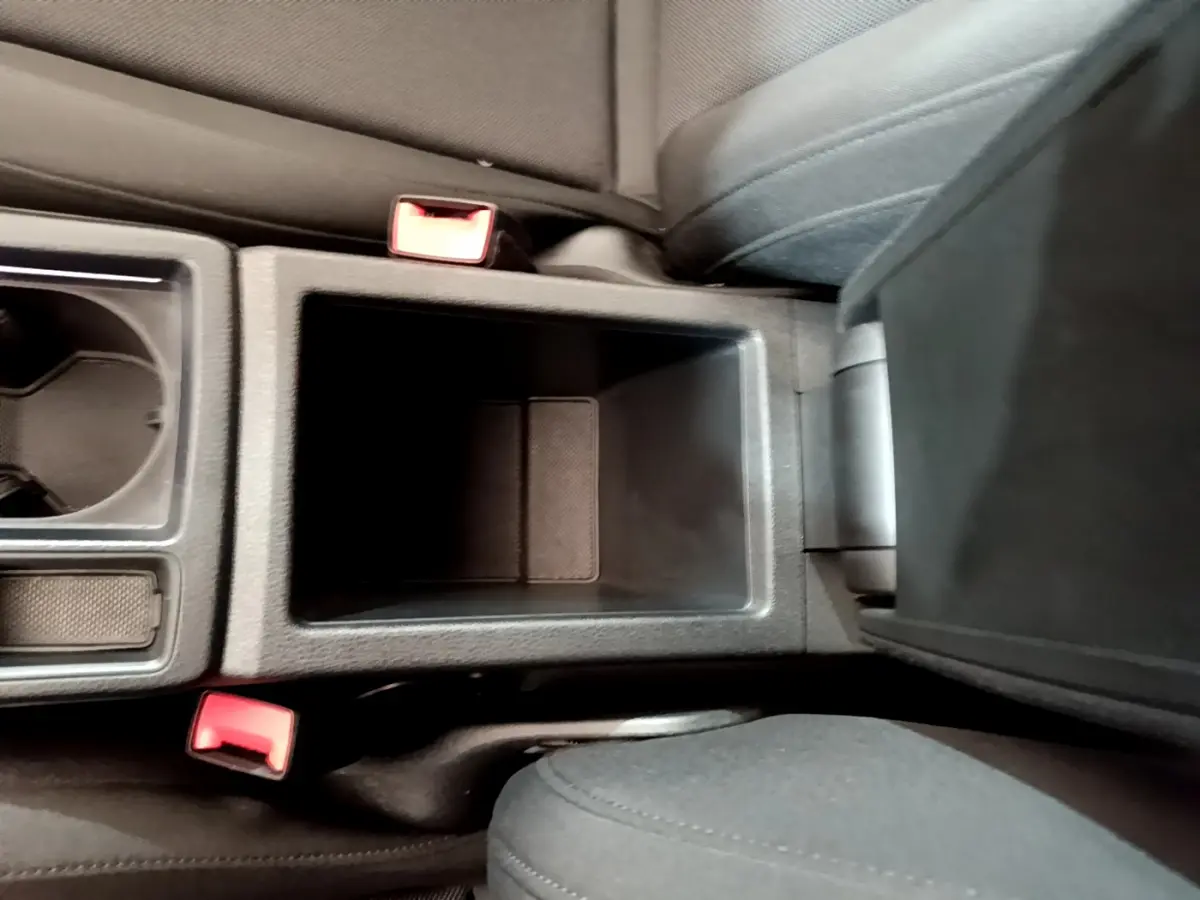 Vue plongeante sur la console centrale noire de l'Audi Q3 Sportback 2021, avec porte-gobelets et accoudoir ouvert.