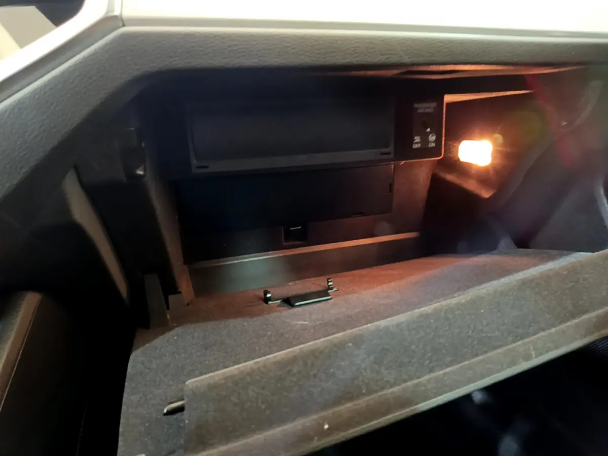 Intérieur de la boîte à gants ouverte de l'Audi Q3 Sportback noir, éclairée par une petite lampe intérieure.