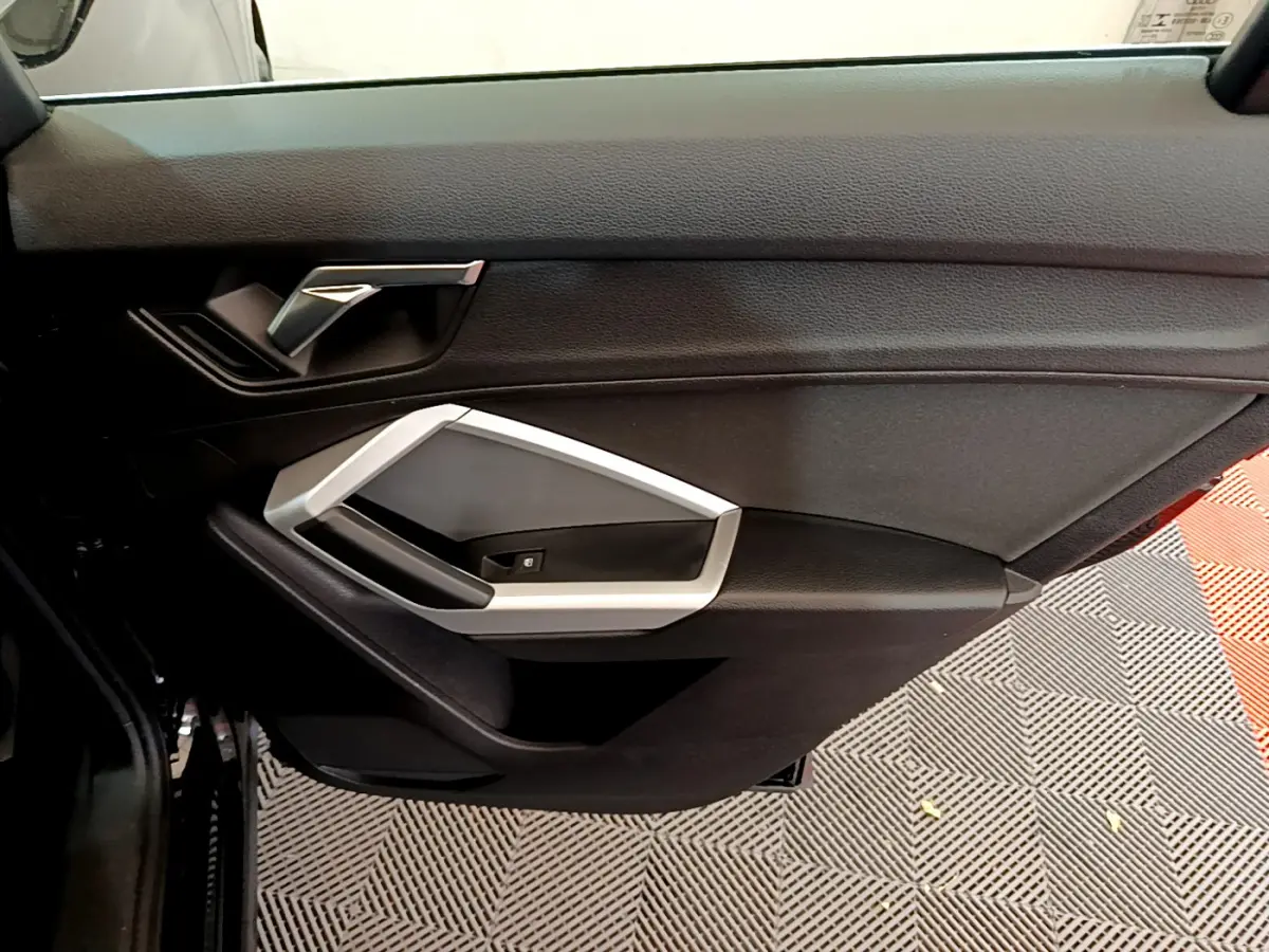 Gros plan sur la porte côté gauche noire de l'Audi Q3 Sportback 35 TFSI 150 MHEV avec poignée argentée.