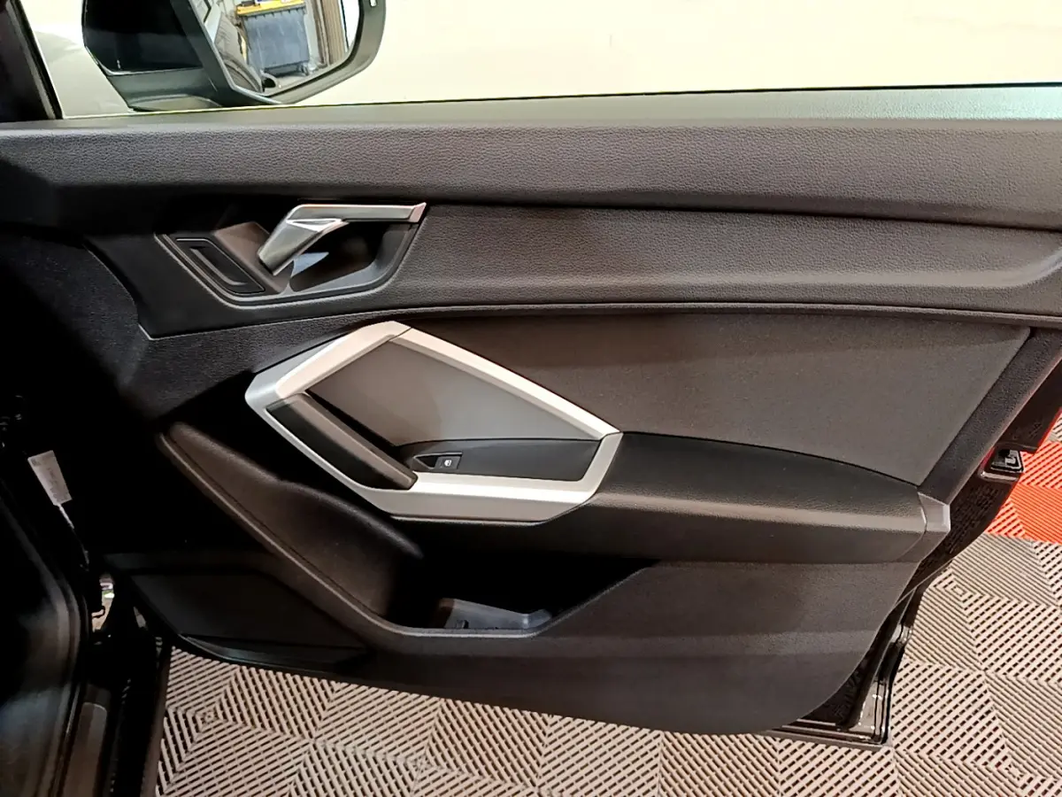 Intérieur noir de la porte côté gauche de l'Audi Q3 Sportback 2021 avec poignée argentée et commandes de fenêtre.