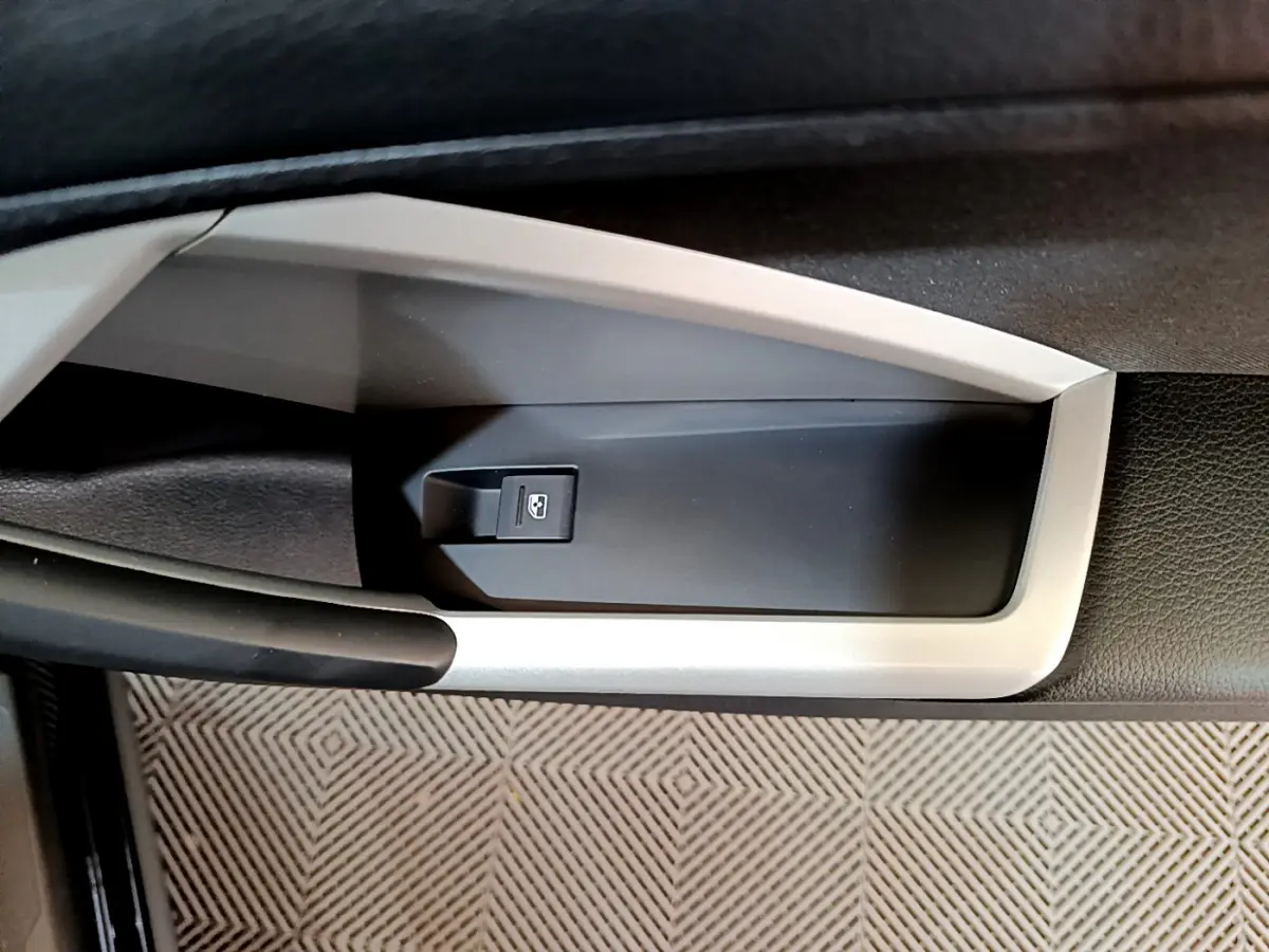 Détail de la commande d'ouverture du coffre sur la porte intérieure côté gauche d'un Audi Q3 Sportback noir 2021.
