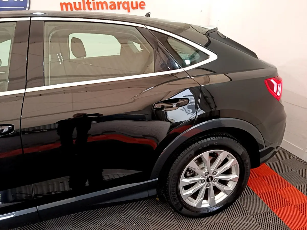 Vue latérale droite de l'Audi Q3 Sportback noir, mettant en valeur la roue arrière et la ligne de toit plongeante.