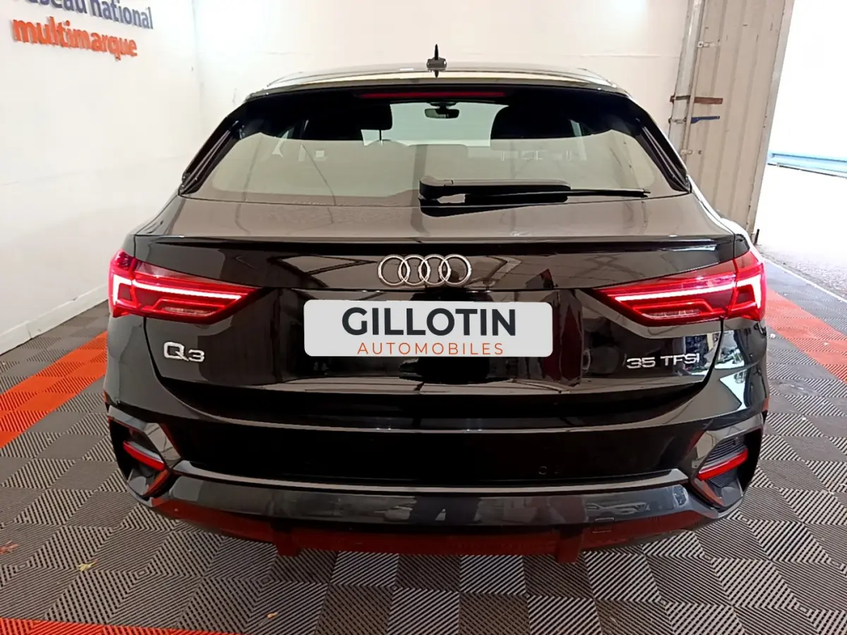 Vue arrière d'un Audi Q3 Sportback noir 35 TFSI avec feux LED allumés dans un garage fermé.