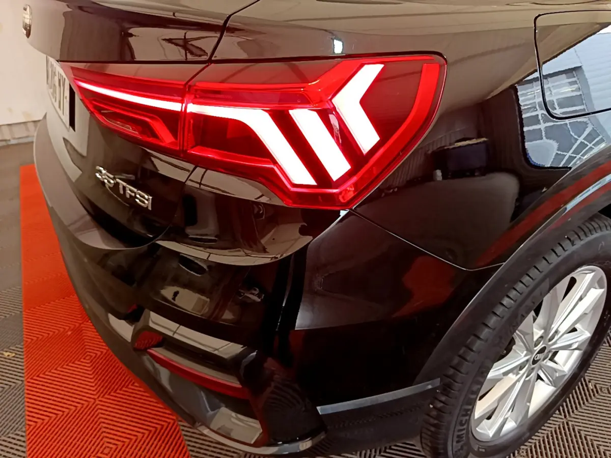 Gros plan sur le feu arrière droit rouge d'un Audi Q3 Sportback noir, avec logo 35 TFSI visible sur le coffre.