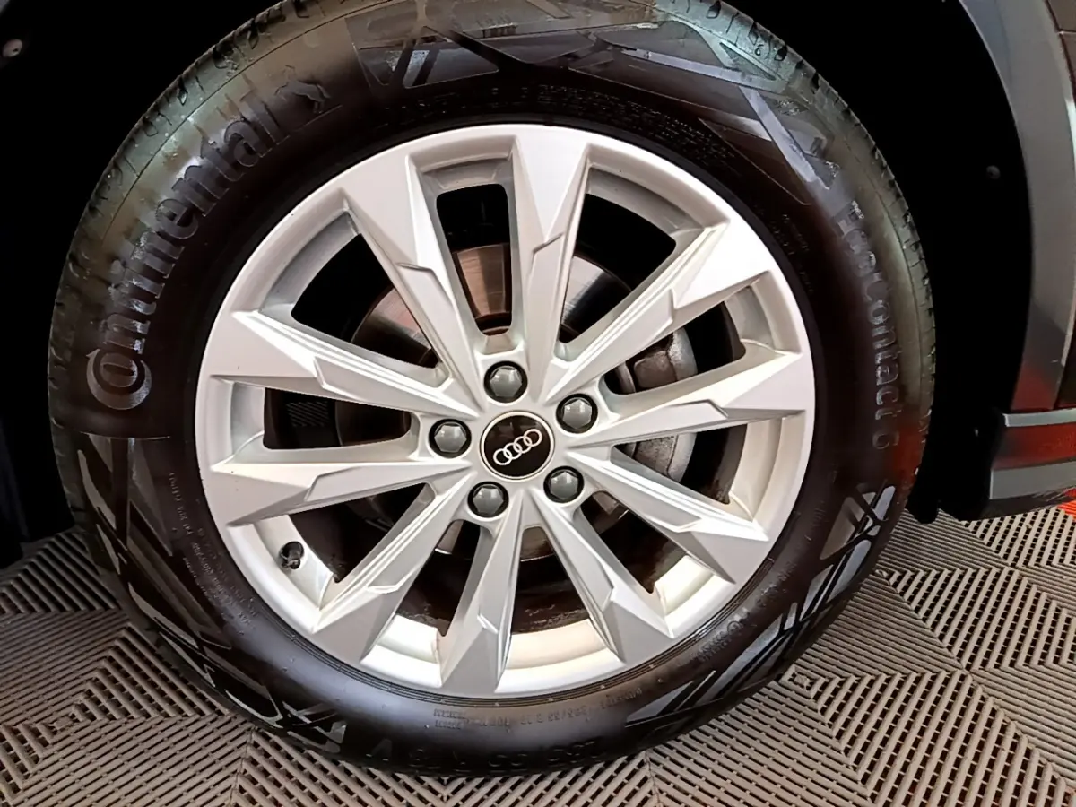 Gros plan sur la roue avant droite d'un Audi Q3 Sportback noir, mettant en valeur la jante en alliage argentée à 10 branches.