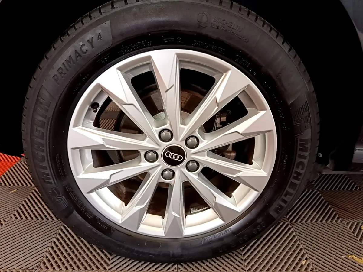 Gros plan sur la jante argentée de l'Audi Q3 Sportback noir, mettant en valeur le logo Audi central.