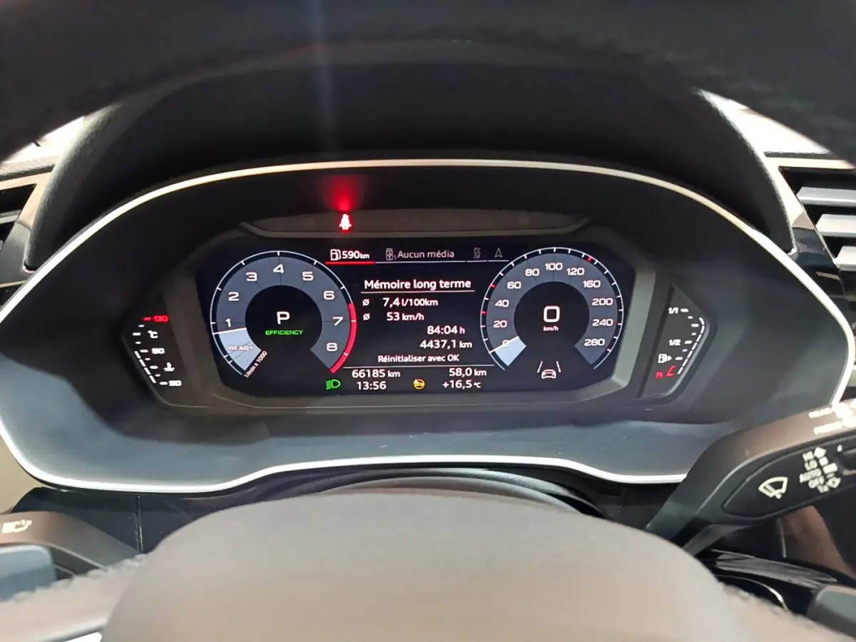 Tableau de bord numérique de l'Audi Q3 Sportback noir, affichant vitesse, consommation et informations de conduite.