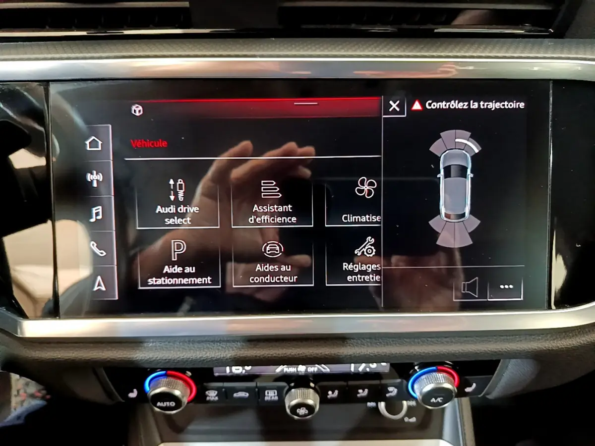 Écran tactile central de l'Audi Q3 Sportback noir 2021 affichant les aides à la conduite et la climatisation.