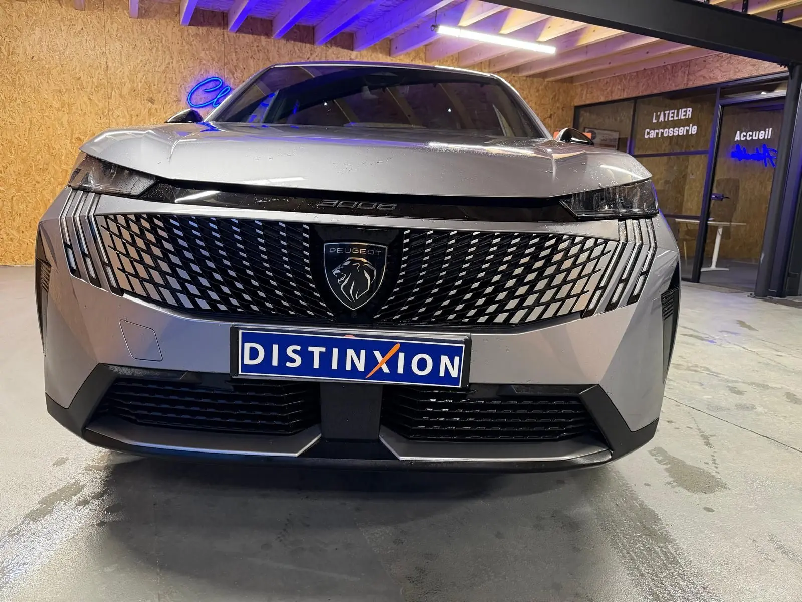 Vue avant rapprochée du Peugeot 3008 gris 1.2 HYBRID 136 Allure avec calandre distinctive et logo lion central.