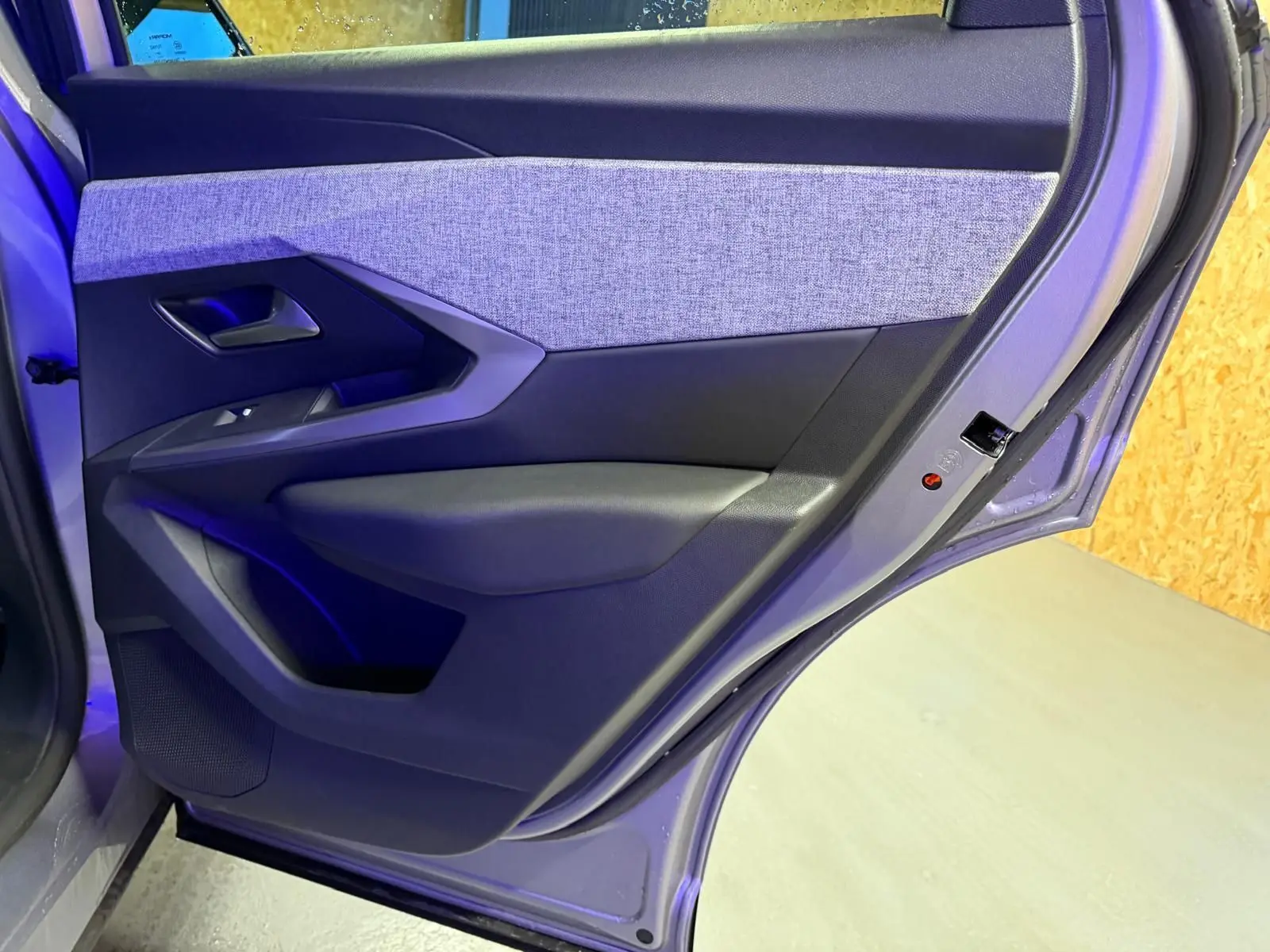 Vue rapprochée de la porte arrière gauche gris clair du Peugeot 3008 1.2 HYBRID 136 Allure avec habillage tissu et plastique noir.