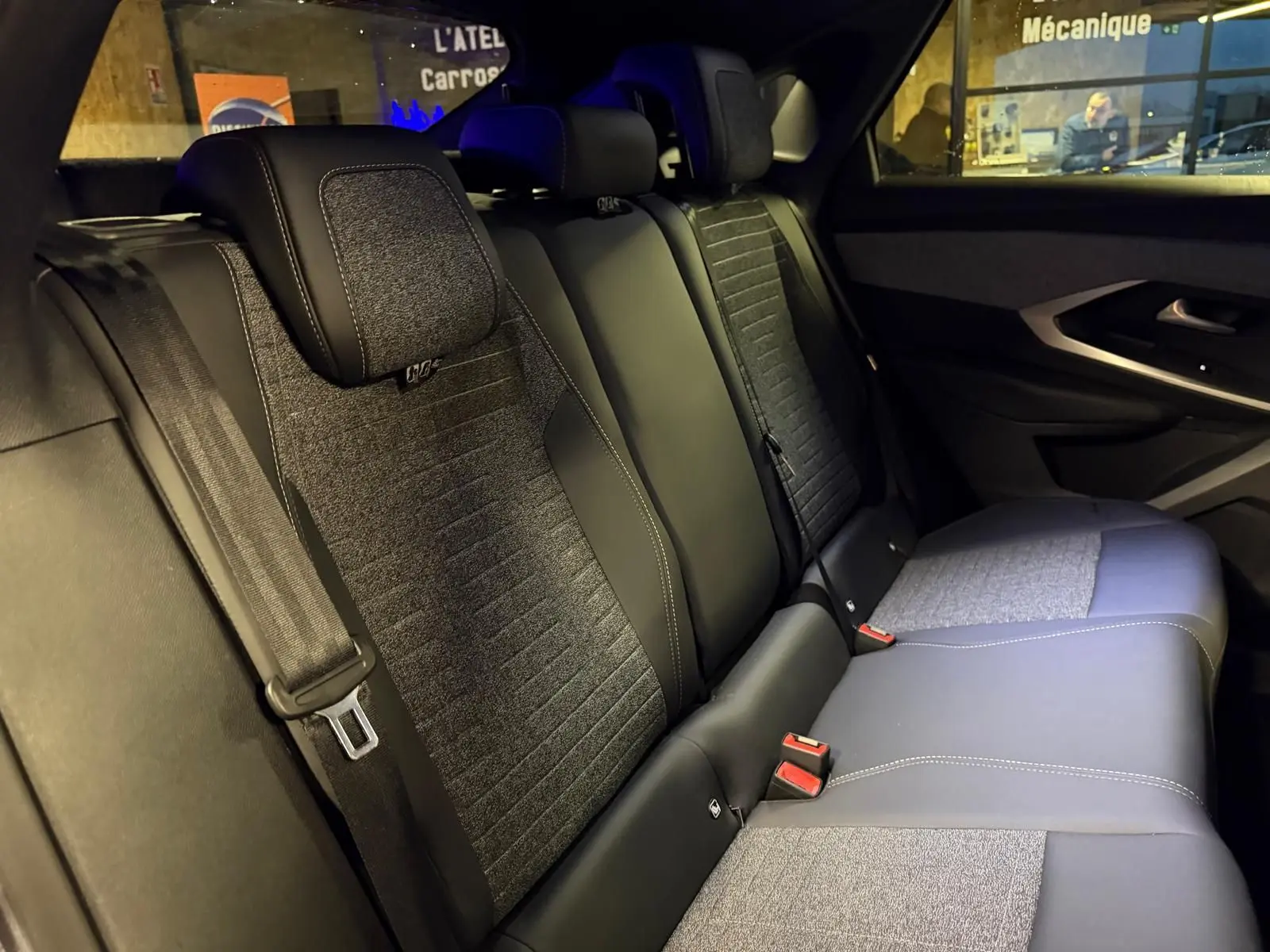 Vue intérieure des sièges arrière en tissu gris et noir du Peugeot 3008 1.2 Hybrid 136 Allure, ambiance tamisée.