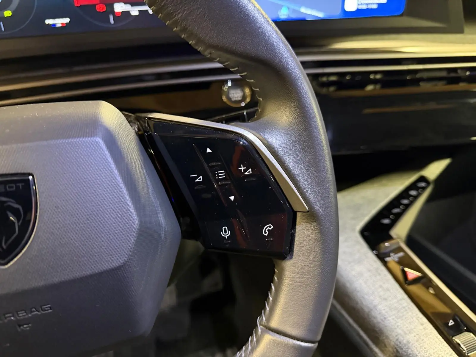 Gros plan sur le volant cuir noir du Peugeot 3008 1.2 Hybrid 136 Allure avec commandes vocales et téléphone intégrées.