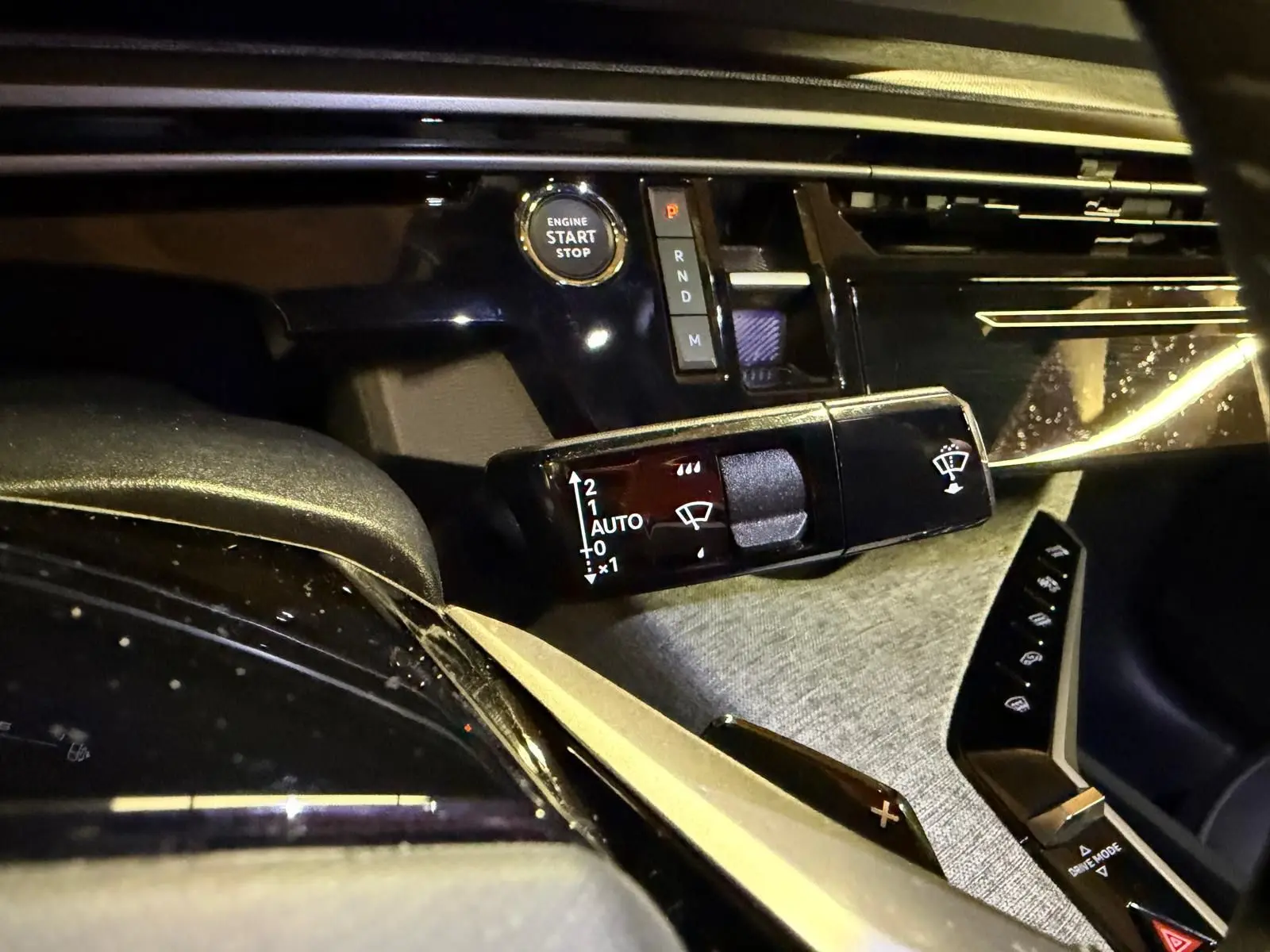 Détail intérieur du tableau de bord du Peugeot 3008 gris, avec bouton start/stop et commande essuie-glace.