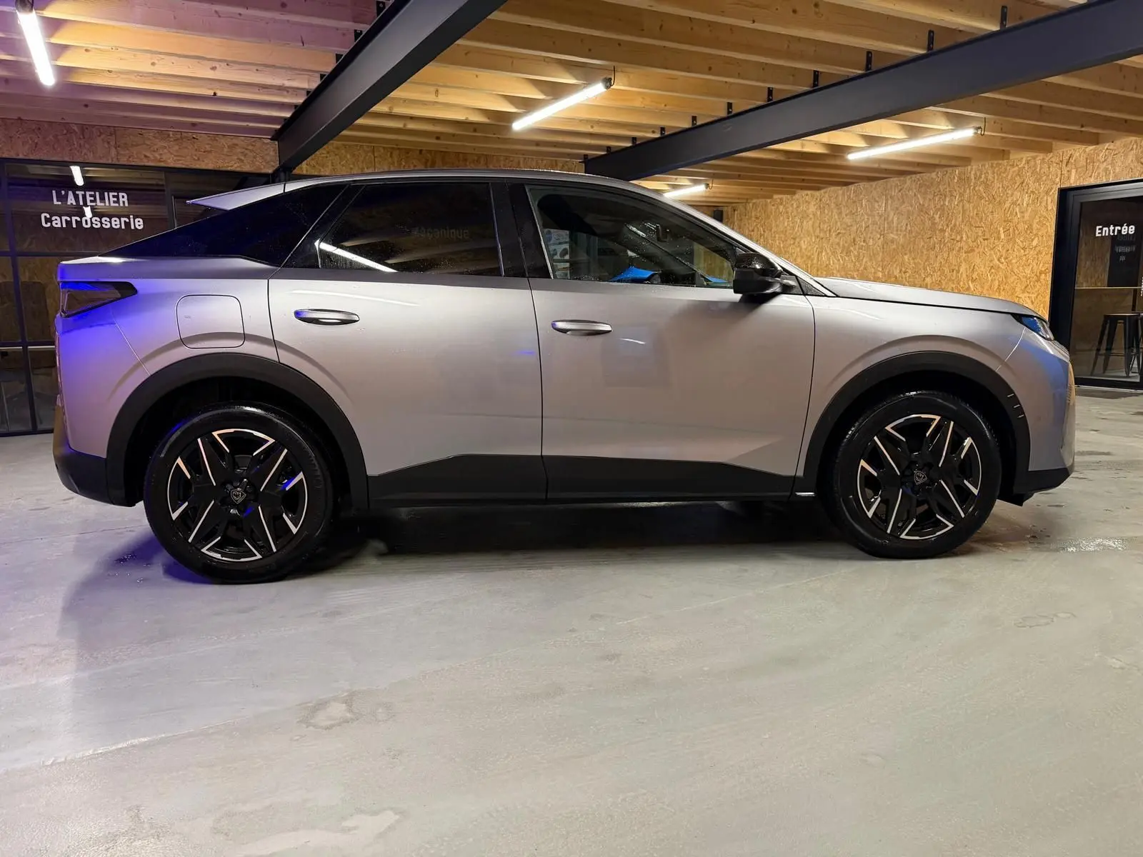 Peugeot 3008 1.2 Hybrid 136 Allure gris en vue de profil côté gauche, roues alliage noires, intérieur sombre visible.