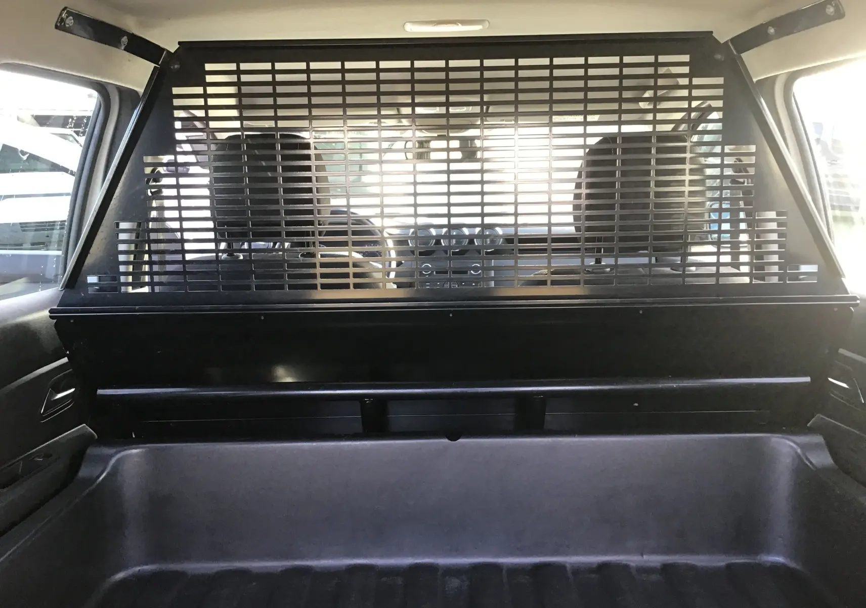 Vue intérieure arrière du Dacia Duster blanc 2021, mettant en valeur la grille de séparation entre coffre et habitacle.