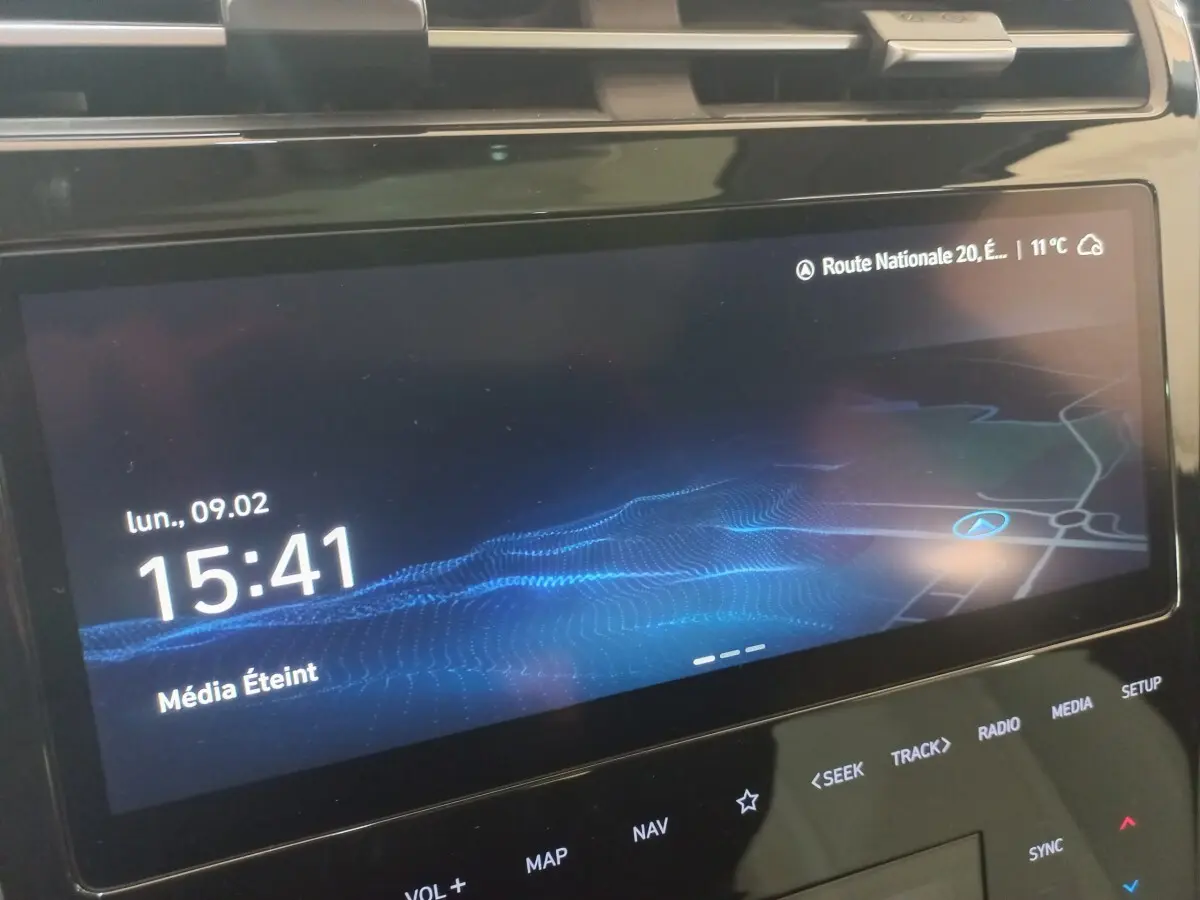 Écran tactile central du Hyundai Tucson gris foncé 2023 affichant l'heure et la navigation.