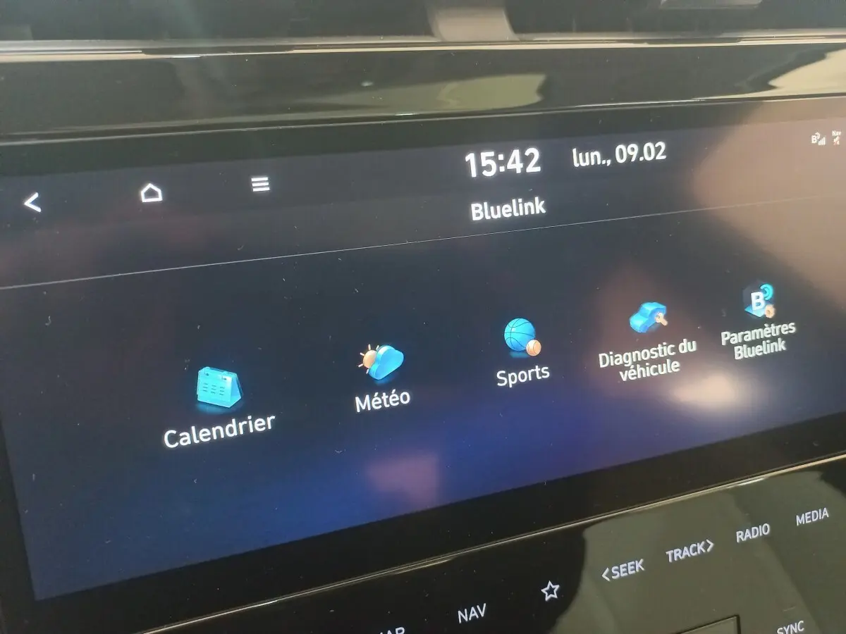 Écran tactile central du Hyundai Tucson 2023 affichant les applications Bluelink sur fond noir, vue rapprochée.