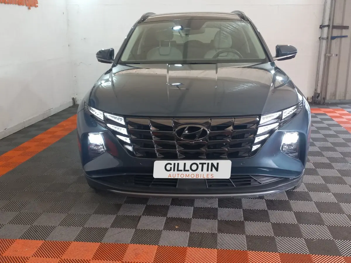 Vue avant d'un Hyundai Tucson gris foncé 2023 avec calandre noire et phares LED allumés en intérieur.